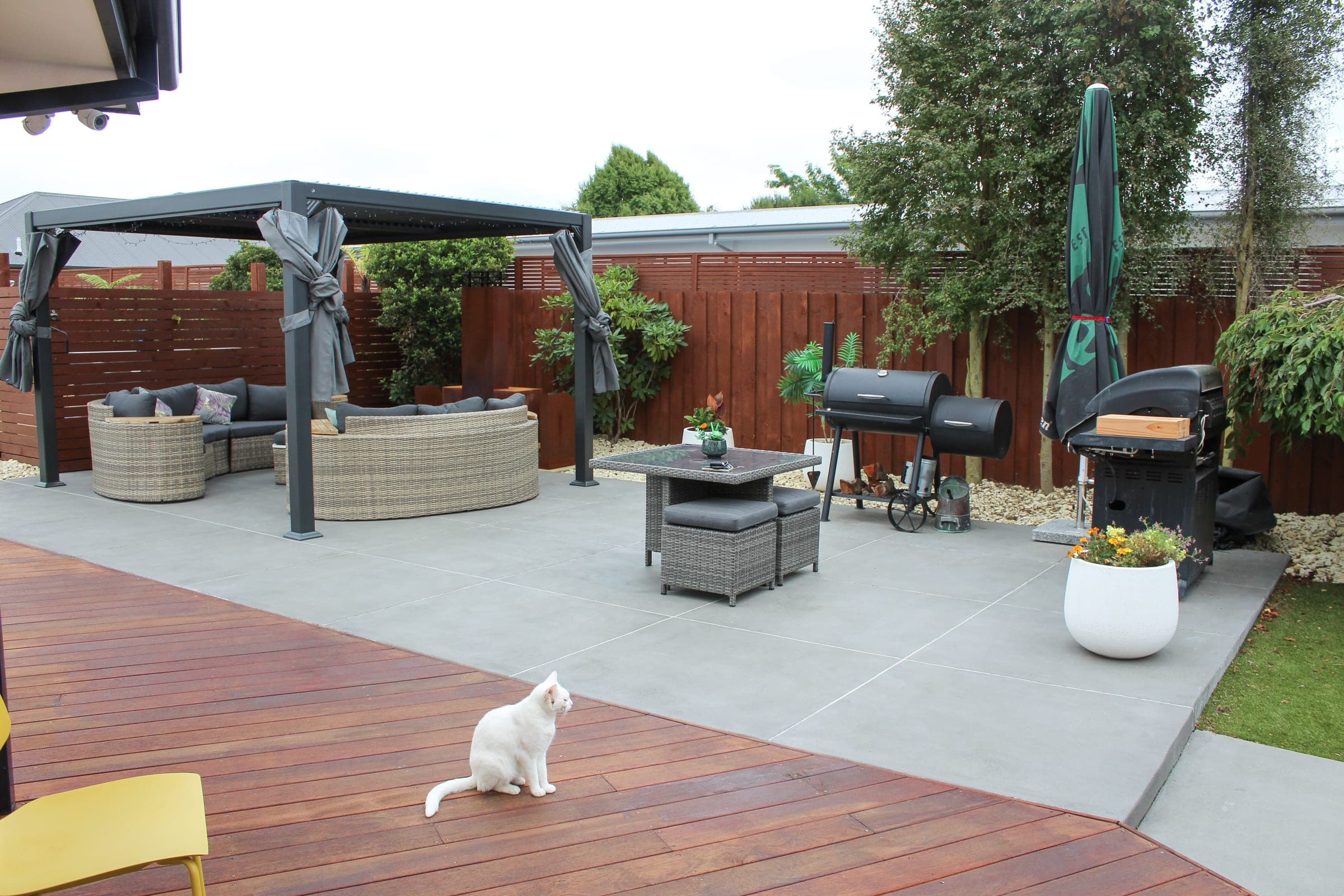 Warm hardwood decking meeting the paved entertaining area — set up for summer.